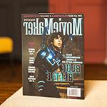 桌上放着一本《电影制作人》杂志. 封面上是一个穿着蓝色甲壳虫服装的演员. 标题是“25所最佳电影学院” & “最酷的电影节”横贯顶部.